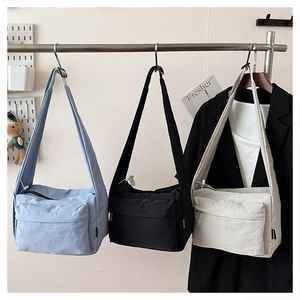 Three colors of waterproof nylon crossbody bags hanging on display for casual use