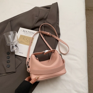 Detail view of the pink lychee leather texture and silver buckle on a minimalist handbag