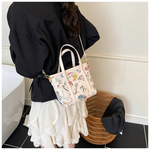 Vue détaillée du sac cabas crème avec graffitis colorés et fine bandoulière réglable