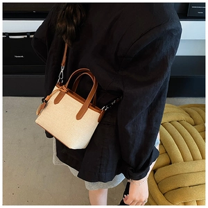 Detail of beige woven bucket bag with brown leather trim worn with a black blazer
