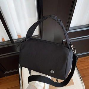 Détail du sac Boston noir avec poignée froncée en nuage et bandoulière large en tissu