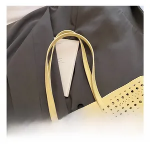 Detailed close-up of hollow-out round pattern on pale yellow vegan leather tote bag