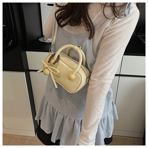 Detail of creamy white patent leather pillow bag with a delicate bow and beaded charm