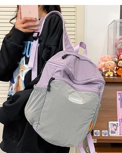 Dettaglio dello zaino in nylon bicolore viola e grigio con etichetta del marchio