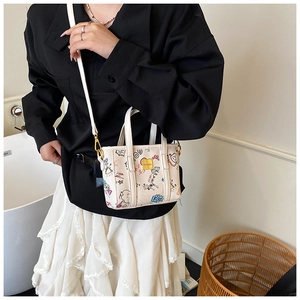 Détail d'un sac seau blanc avec motifs graffitis colorés et bandoulière réglable