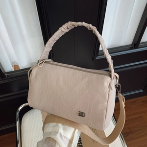 Détail du sac Boston en nylon rose clair avec poignée plissée et logo argenté sur chaise