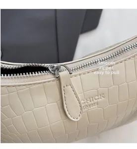 Detailed macro view of smooth metal zipper and crocodile texture on beige bag