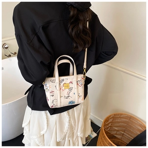 Vue détaillée du sac seau crème avec graffitis colorés et bandoulière réglable