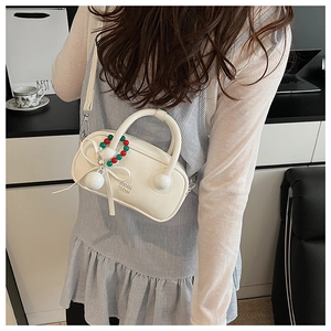 Detailed close-up of white minimalist pillow bag with contrast beads and bow charm