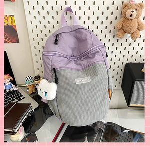 Dettaglio dello zaino in nylon con contrasto viola e ciondolo in peluche a forma di nuvola