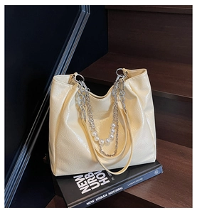 Detail of beige tote bag with pleated oil wax texture, pearl chain and metal strap