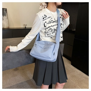 Detailed view of light blue nylon crossbody bag on model with wide strap and zip pocket