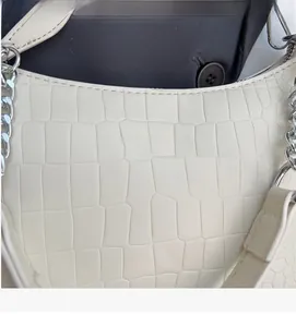Macro detail of creamy white crocodile pattern PU leather with embossed logo and chain