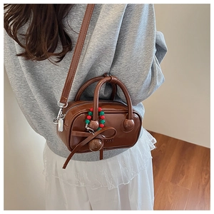Detailed view of a brown vintage pillow bag with beaded bow charm and 2DN logo