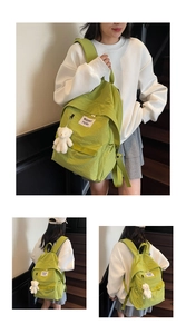 Detail view of grass green nylon backpack with white bear plush charm on indoor stairs