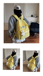 Detail of yellow nylon backpack with white textile label and cute teddy bear pendant