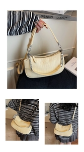 Detail of off-white baguette bag with faux crocodile texture and silver chain strap