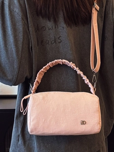Sac Boston rose avec poignée plissée porté en bandoulière stylée sur un mannequin