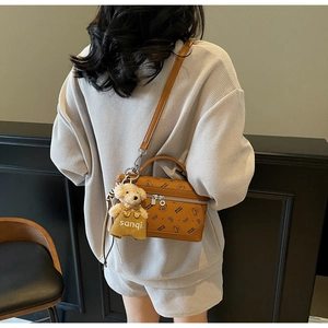 Detail of brown leather mini crossbody bag with cartoon bear print and plush toy charm