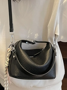 Minimalist black pebbled leather tote bag with silver hardware and woven rope charm
