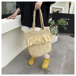 Detailed texture of bohemian woven straw tote bag with elegant tassel fringe accents