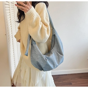 Close-up of blue denim hobo bag featuring knotted shoulder strap and crescent moon shape