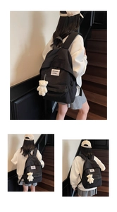 Close-up of black minimalist backpack with white label and cute plush bear charm detail