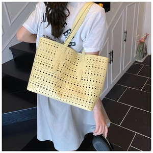 Detailed close-up of a large yellow hollow-out tote bag with laser-cut geometric patterns