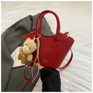 Dettaglio della borsa a secchiello rossa intrecciata con logo in metallo e ciondolo orso