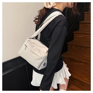 Detailed side view of a cream-white nylon crossbody bag showing zippers and wide strap