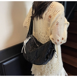 Detail of black pleated hobo bag with white rope knot accent worn by a model