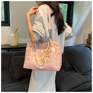 Pink heart-embossed tote bag with colorful beaded chain detail shown on shoulder