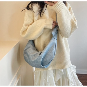 Detailed close-up of a blue crescent croissant bag worn with casual summer outfit