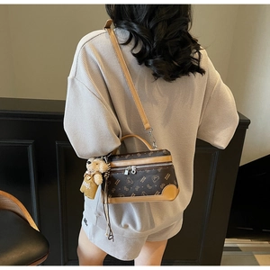 Detail of retro brown leather cylinder bag with bear pattern and plush bear charm