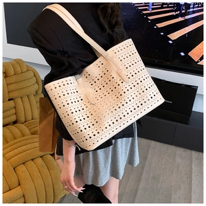 Detail of laser-cut hollow pattern on cream tote bag shown on model's shoulder