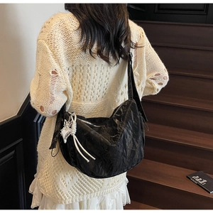 Detail of black pleated hobo bag with silver butterfly charm and soft texture
