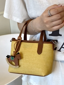 Minimalist yellow canvas tote bag with brown leather handles and rocking horse charm