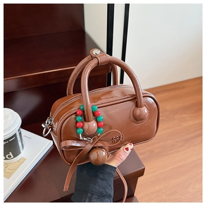 Detail of vintage brown patent leather handbag with beaded charm and ribbon bow decoration