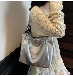 Detail of silver metallic tote bag with pearl chain decoration on shoulder strap