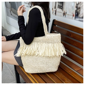 Detailed view of the bohemian woven straw bag featuring decorative white fringe tassels