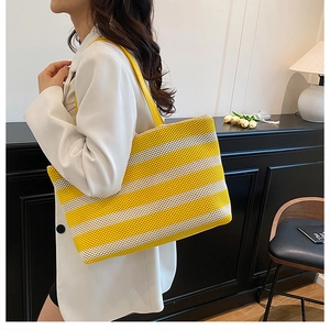 Dettaglio della borsa tote intrecciata a righe gialle e bianche con cinturini in pelle