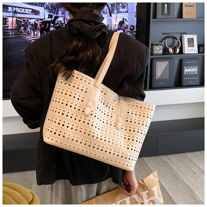 Detailed shot of beige hollow-out tote bag featuring laser-cut patterns and soft leather