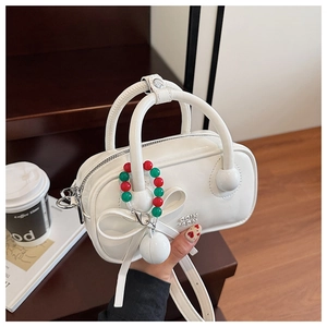 Close-up of white pillow bag with decorative bow and colorful beaded keychain charm