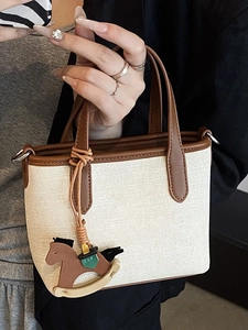 Minimalist canvas tote bag for women with brown leather trim and wooden horse charm