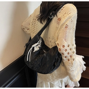 Detail of black pleated shoulder bag with silver heart and butterfly charms