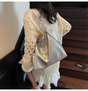 Detail showing the shiny silver tote bag with pearl chain decoration on model's shoulder