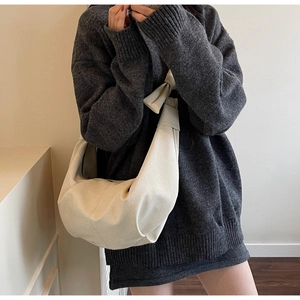 Detail of creamy white crescent bag featuring lychee grain leather and chic bow knot strap