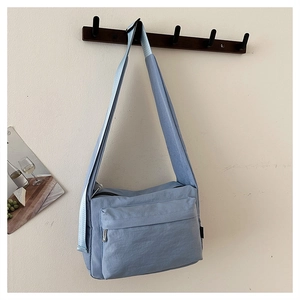 Close-up of light blue waterproof nylon crossbody bag with zipper pocket and strap