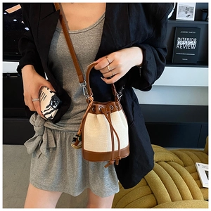 Détail d'un sac seau en toile minimaliste avec garniture en cuir brun et pendentif cheval