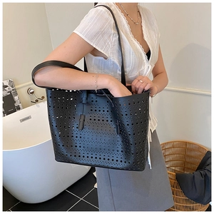 Detailed look at black laser-cut hollow tote bag worn by model in minimalist setting